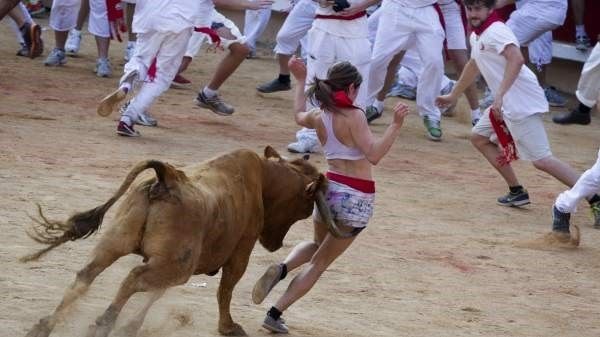 Una joven trata de esquivar la cornada de una vaquilla durante la sexta jornada de encierro de los sanfermines en la plaza de toros de Pamplona. Julio 2013. JIM HOLLANDER / EFE