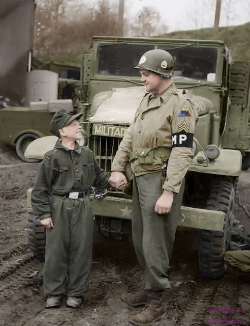 El sargento del personal estadounidense Francis Daggertt de la Policía Militar de la 11ª División Blindada con un joven soldado de la Wehrmacht. El alemán tenía solo 10 años cuando fue capturado en la ciudad alemana de Kronach el 27 de abril de 1945. El hecho de que tales niños en la zona de guerra los expusieran a fuego de artillería y bombardeos, y mucho menos a los otros riesgos de combate, muchos de esos niños eran anónimos, enterrado sin fanfarria, olvidado entre los millones de muertos (coloreados).