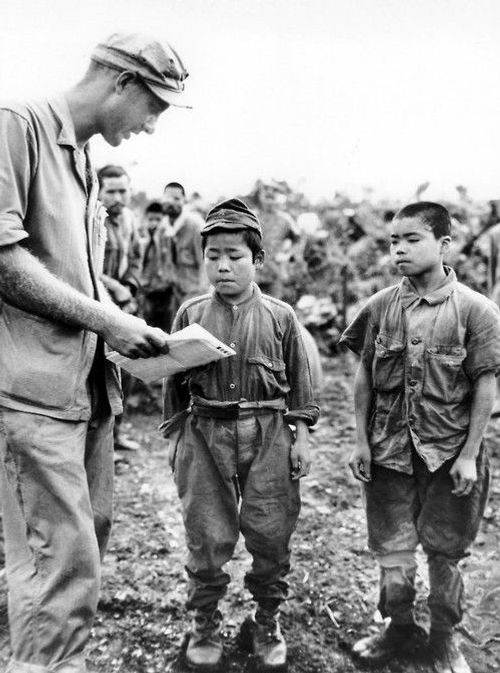 El primer teniente de la Marina de los EE. UU. Hart H. Spiegal intenta comunicarse con dos niños soldados japoneses capturados durante la batalla de Okinawa. 17 de junio de 1945