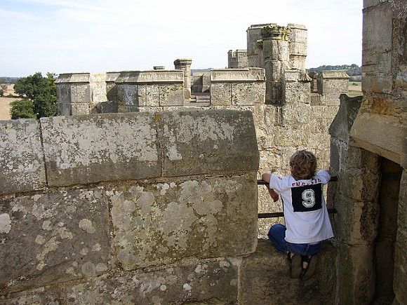 Niño observando el horizonte subido en las murallas del castillo de Bodiam